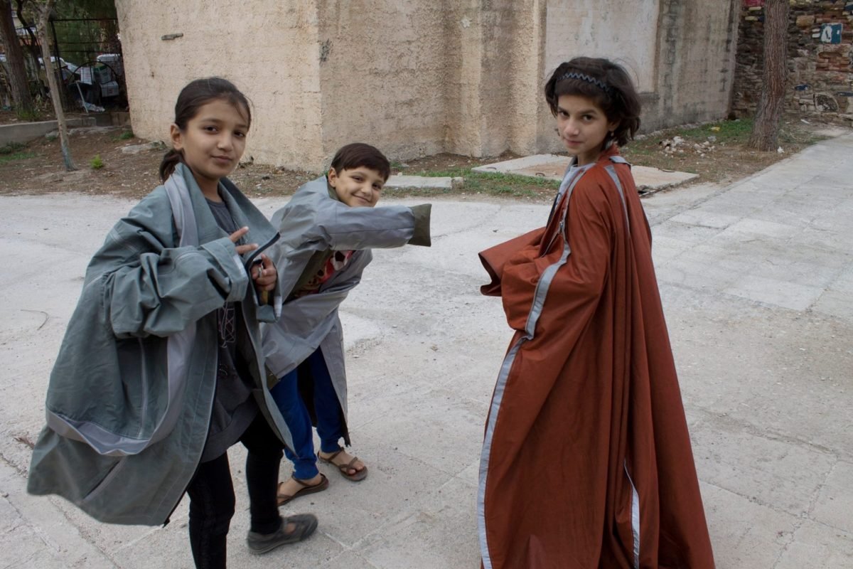 Children in a refugee camp in Greece try on Adiff outerwear