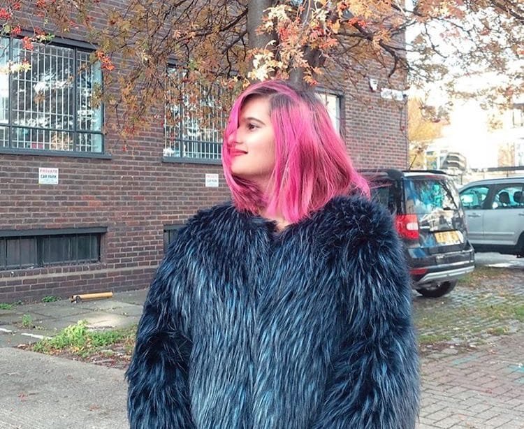 Surbhi Jain, fashion photographer, standing on a London street with iconic architecture in the background.